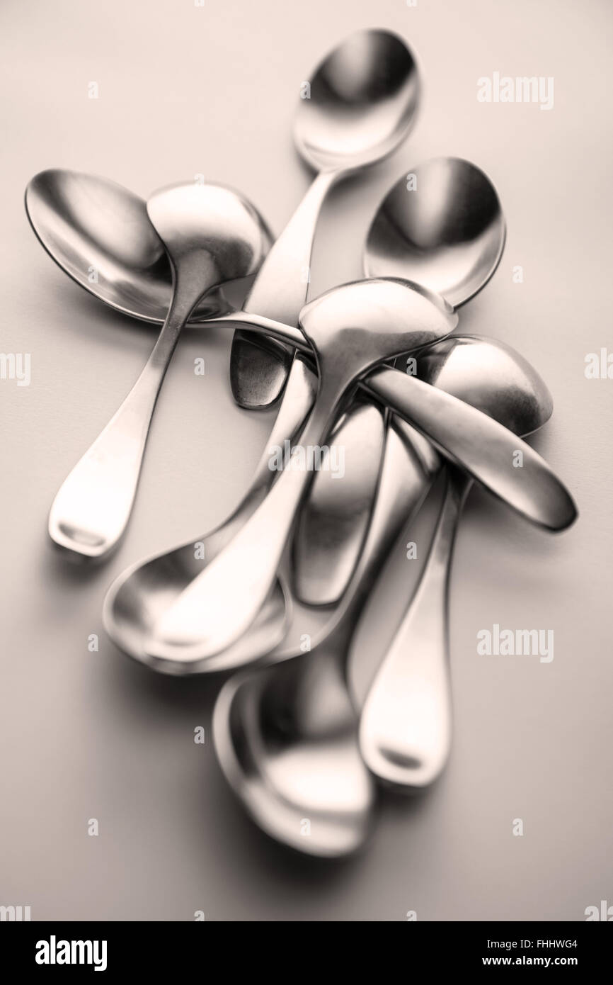 Toned monochromatic black and white, b&w, metal spoons tableware, silverware, grouped and shot on a solid light background. Shot selective focus Stock Photo