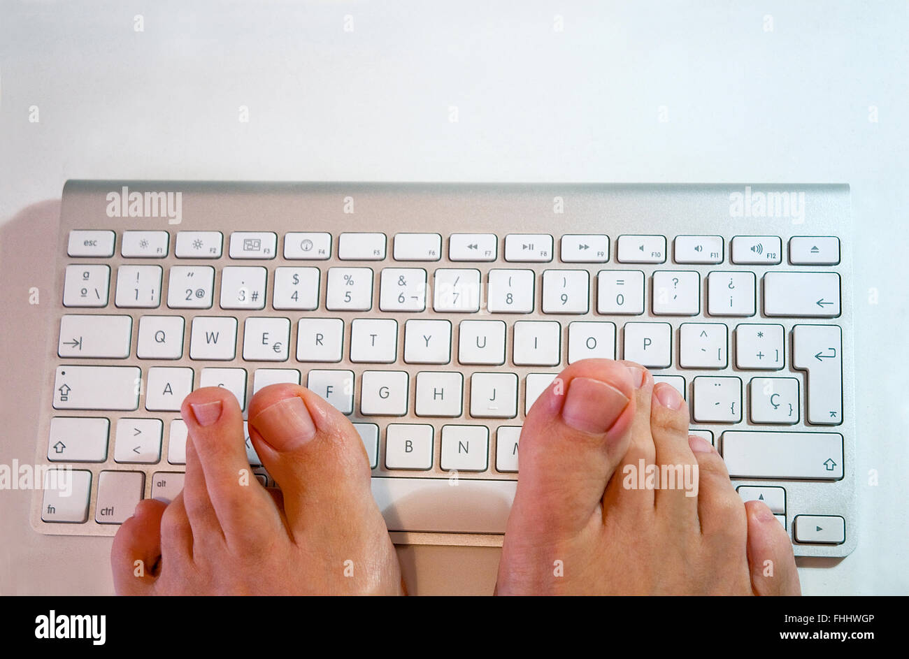 Man's feet typing keyboard. Stock Photo
