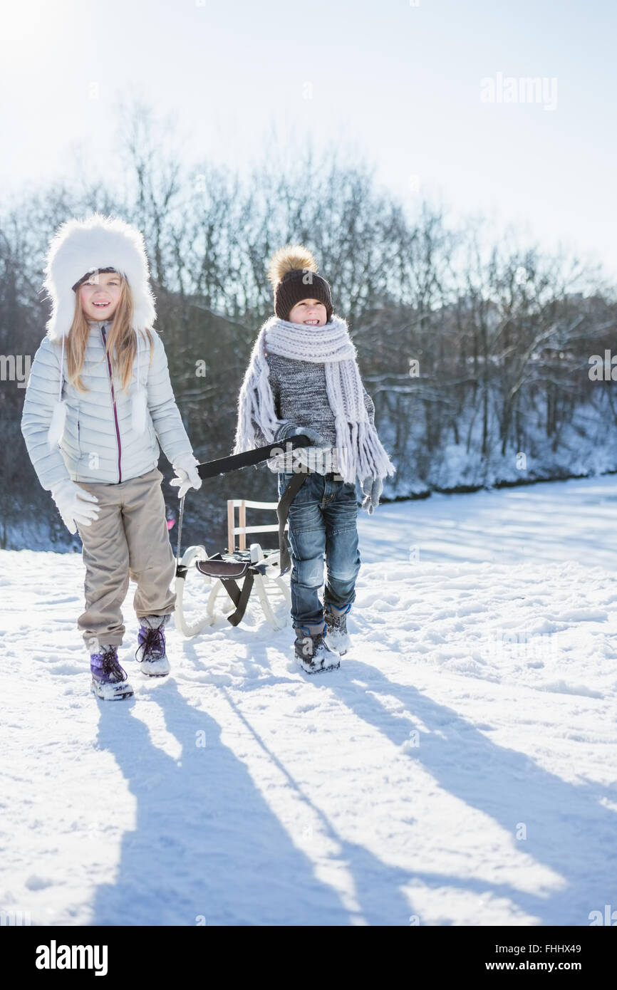 Brother and sister playing with sled Stock Photo - Alamy