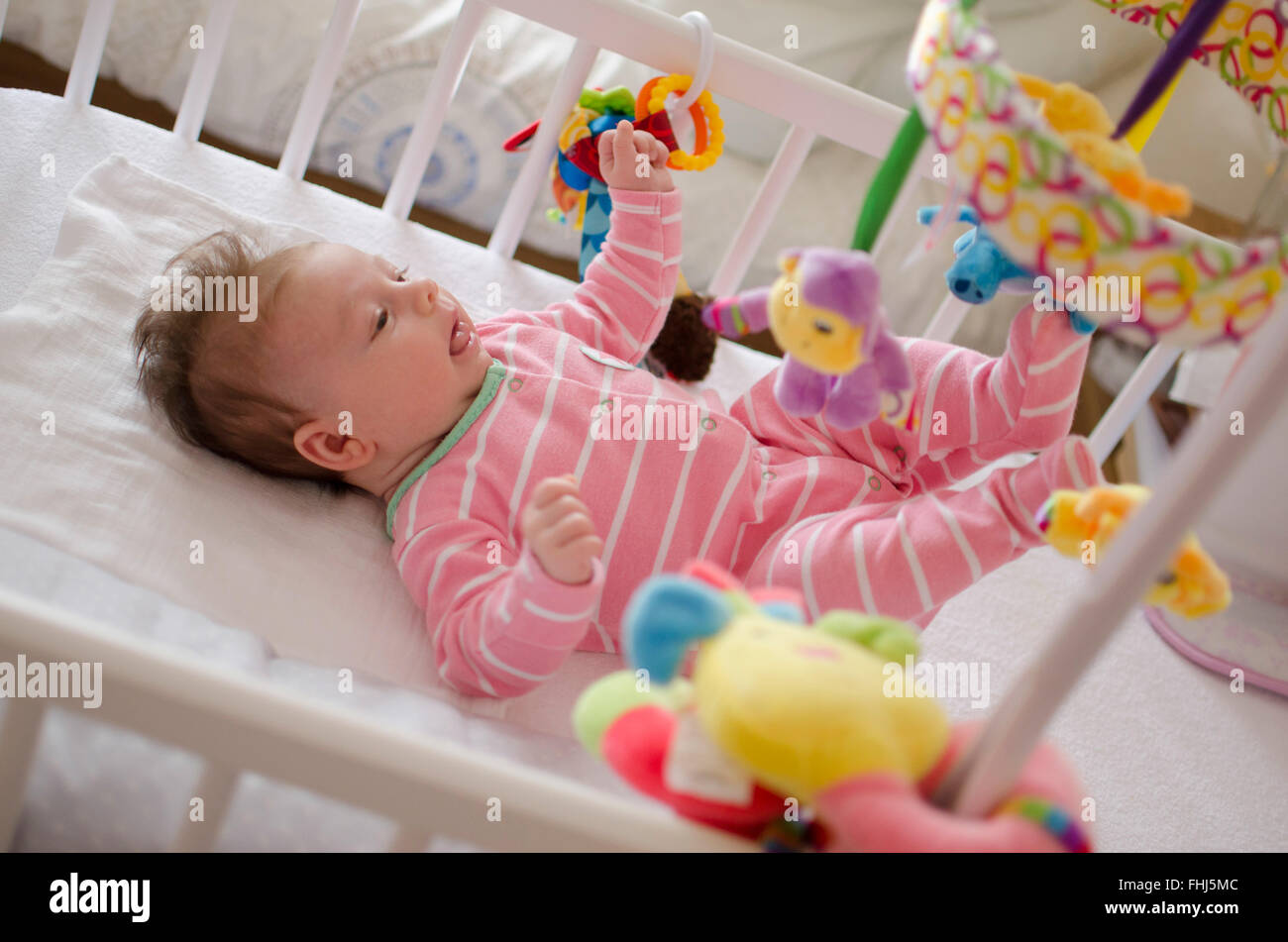 little cute baby girl playing in a cot Stock Photo