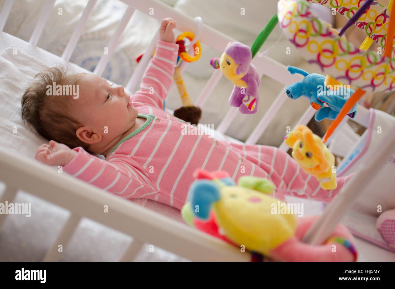 little cute baby girl playing in a cot Stock Photo