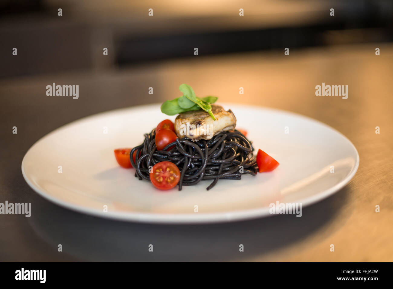 Squid ink spaghetti dish with basil Stock Photo