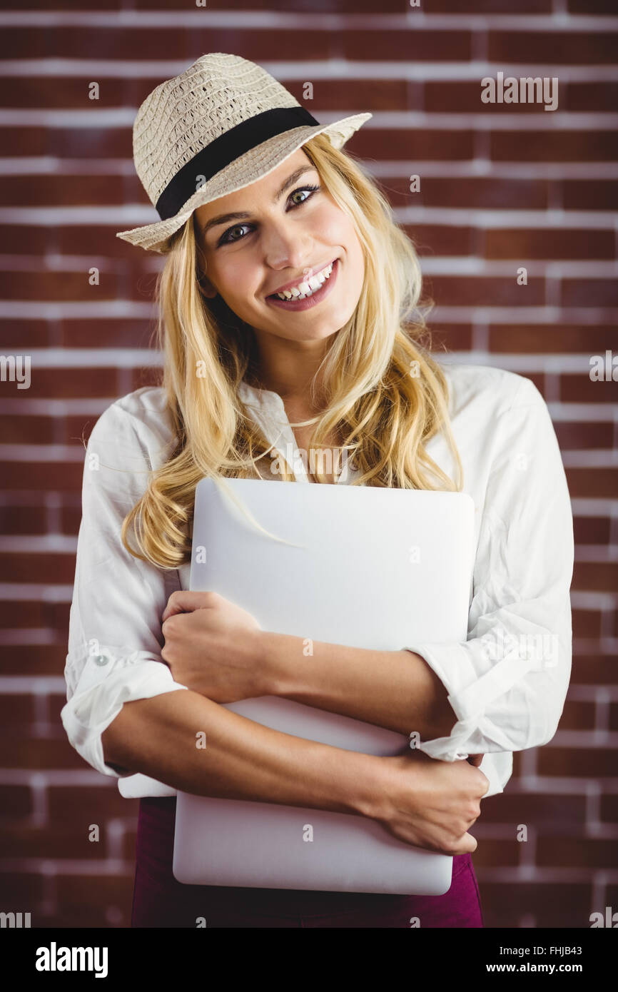 Beautiful blonde woman holding laptop against her chest Stock Photo Alamy