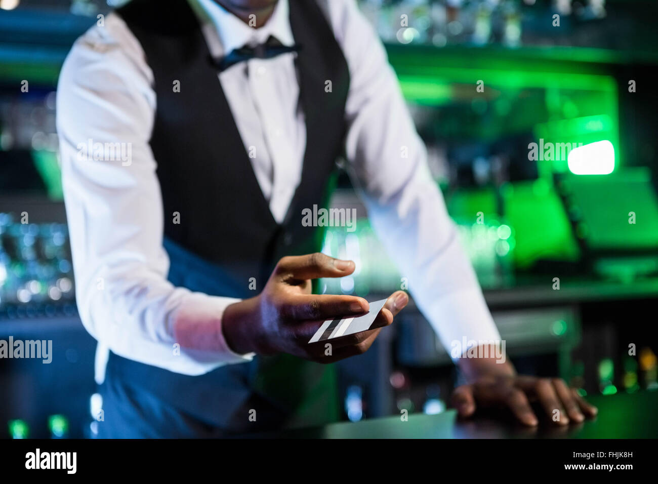 Bartender accepting a credit card at bar counter Stock Photo