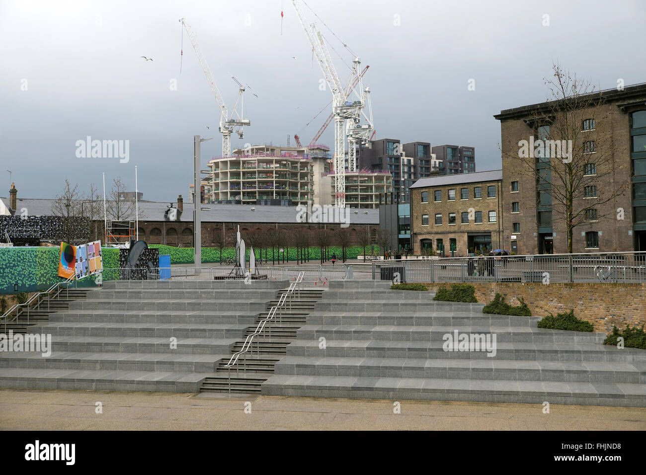 Cranes over Kings Cross gasholders apartment construction site, steps and view of UAL University of the Arts Granary Square, London UK    KATHY DEWITT Stock Photo