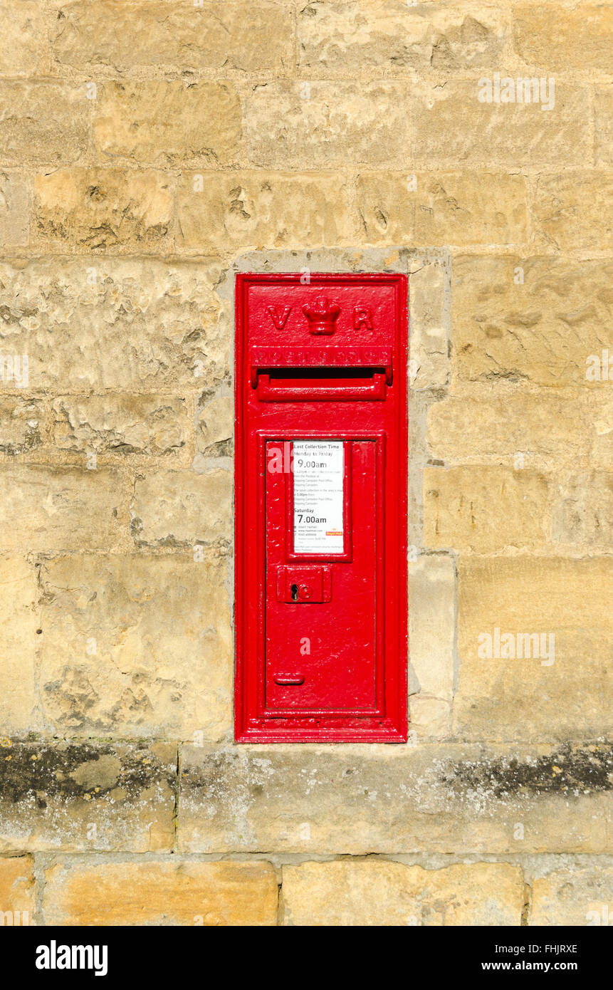 Red post box mounted in wall built from Cotswold stone Stock Photo