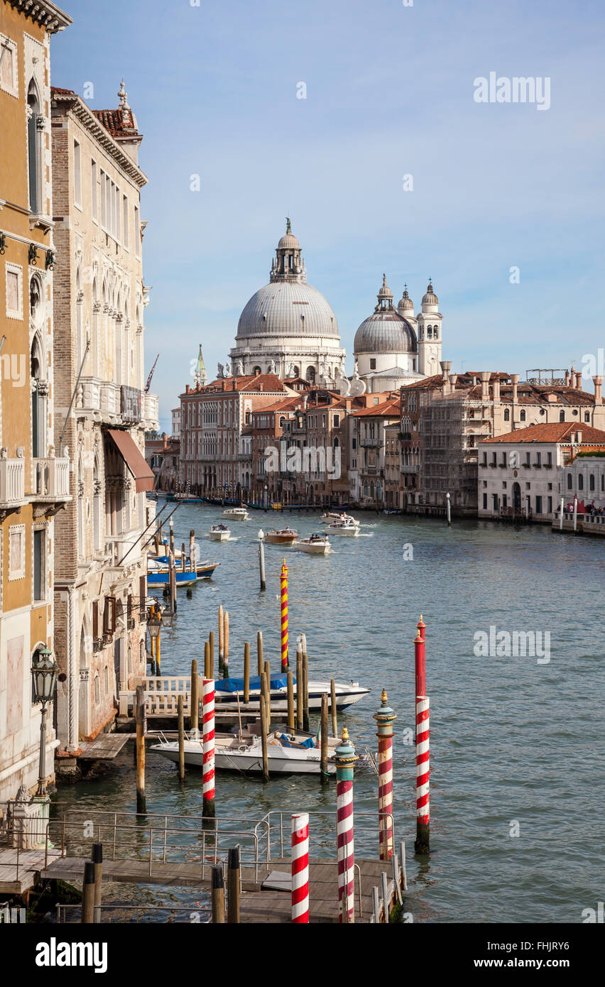 The Grand Canal, red and white mooring poles and the Basilica di Santa Maria della Salute from the Accademia Bridge, Venice, Italy under a blue sky Stock Photo