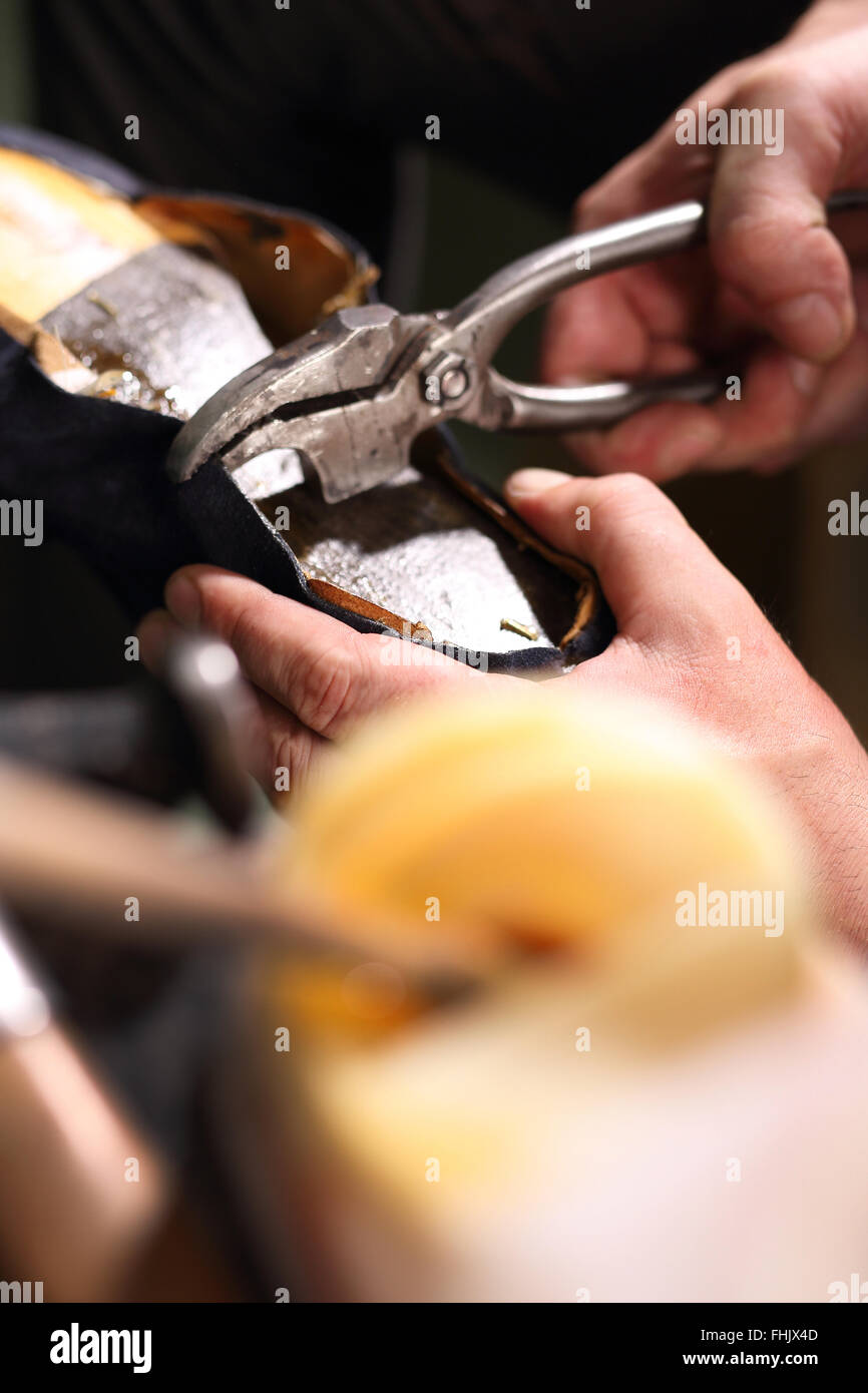 Punch skin for shoes. shoemaker makes chisel holes in the skin grain