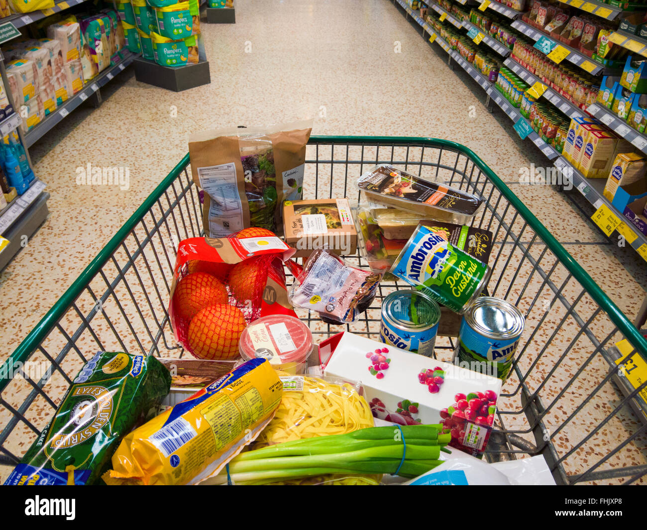Shopping trolley containing groceries in a supermarket aisle. Stock Photo