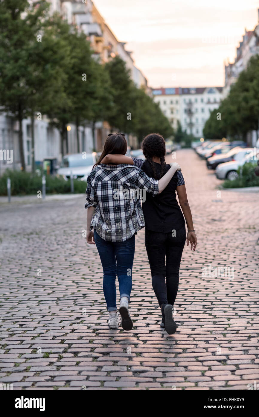 Two Teenage Girls Walking On A Street Arm In Arm Stock Photo Alamy