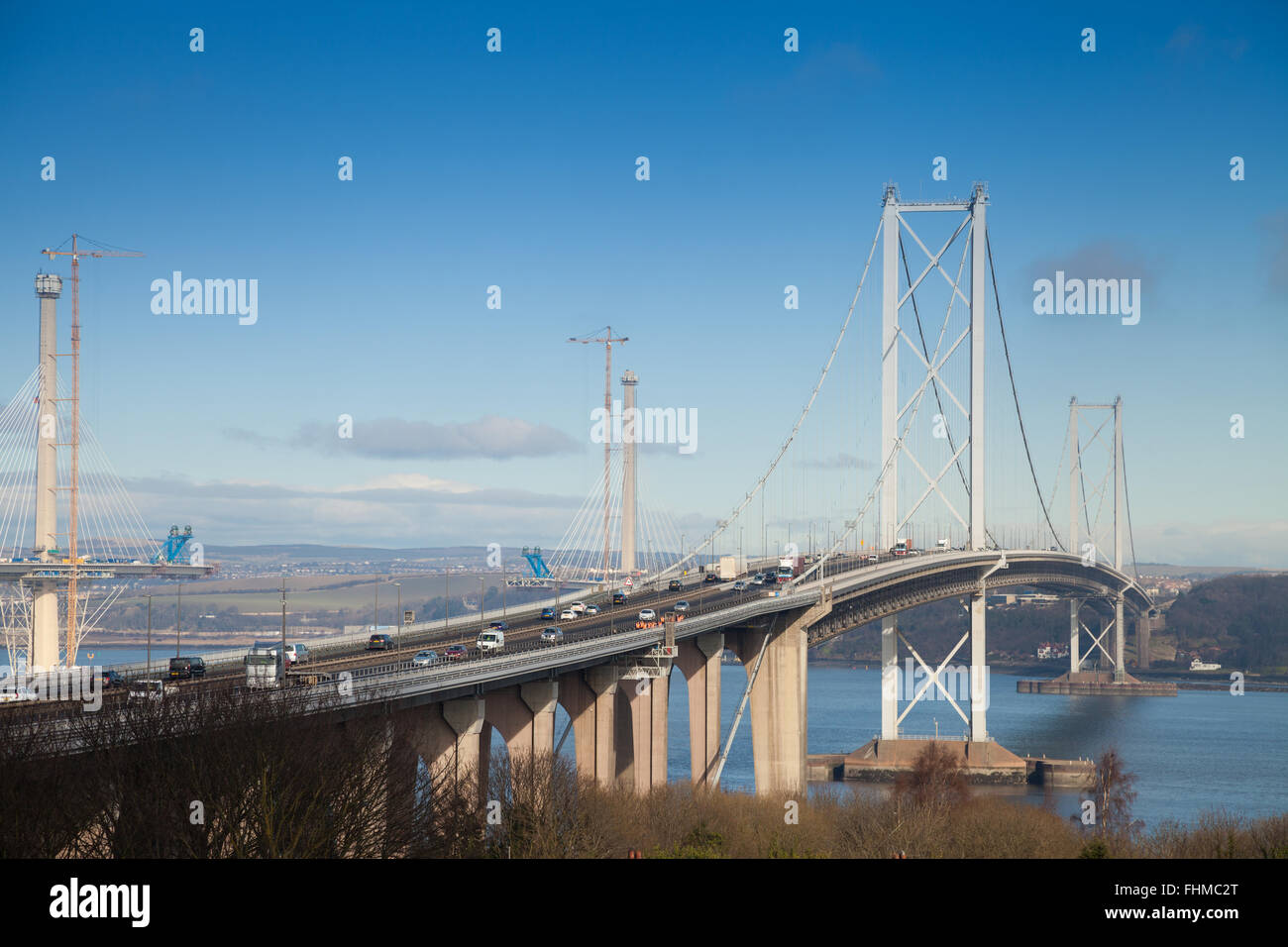 The Forth Road Bridge with the new Queensferry Crossing being built behind near Edinburgh seen from South Queensferry, Scotland. Stock Photo