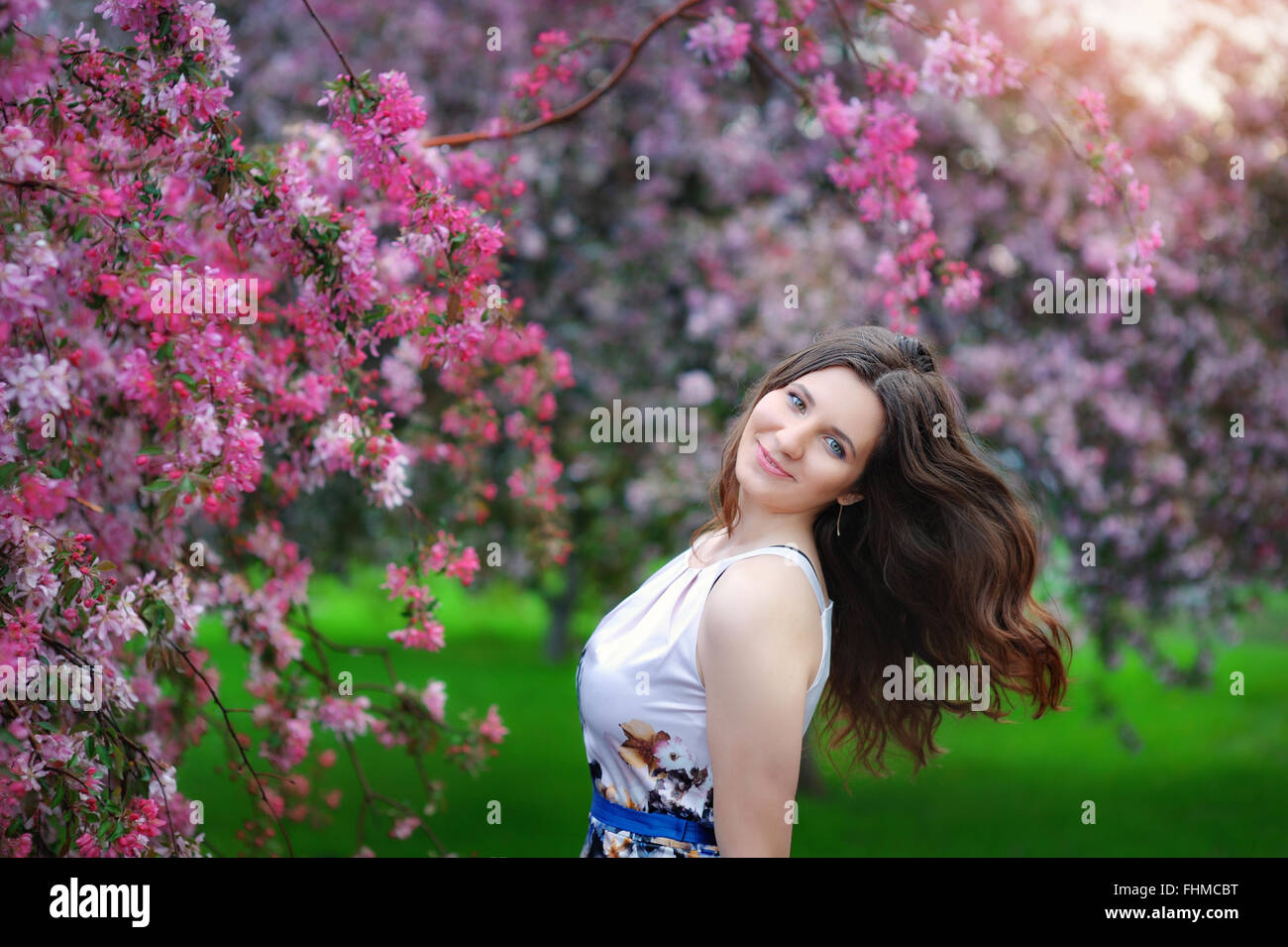 Beautiful young girl in spring flowers garden lifestyle portrait Stock Photo