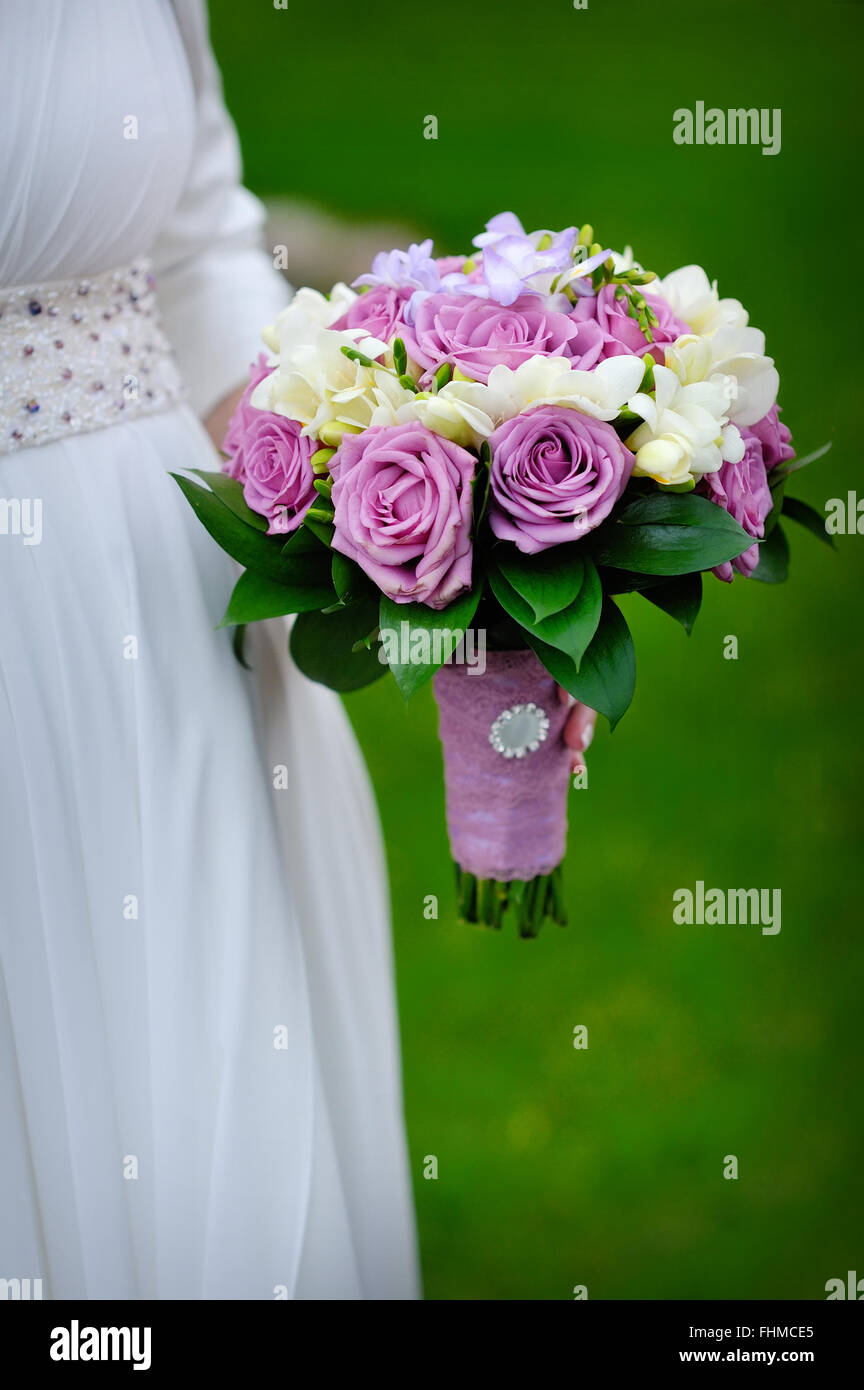 Bridal bouquet of purple roses in bride's hands Stock Photo