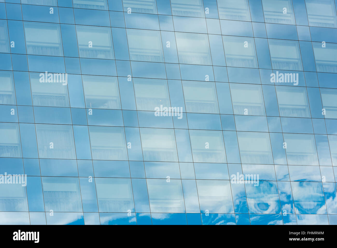 blue sky and clouds reflected in windows of modern office building ...