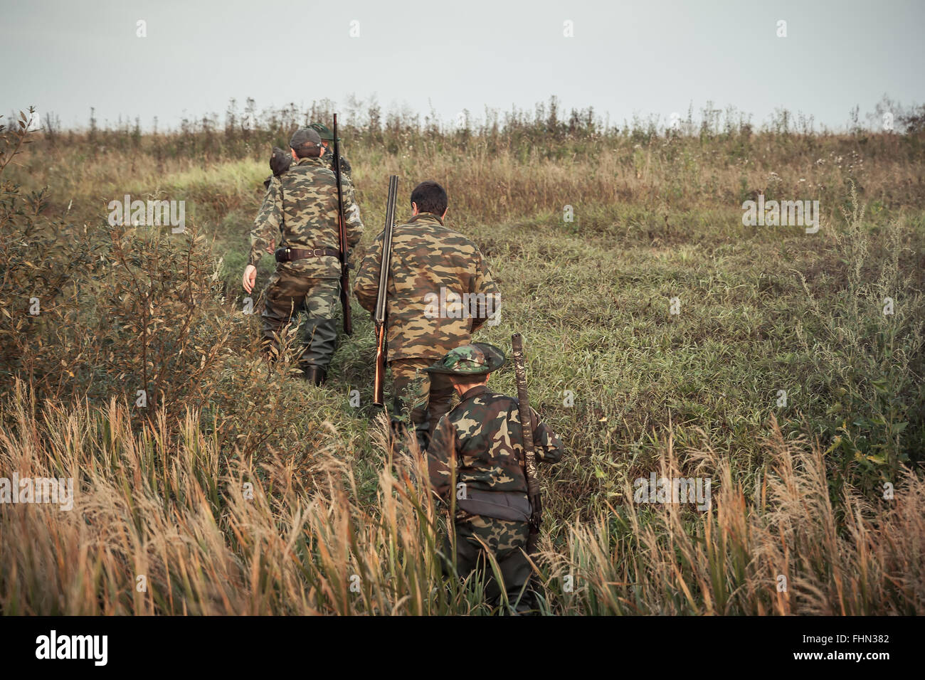 Hunters going up through rural field  during hunting season Stock Photo