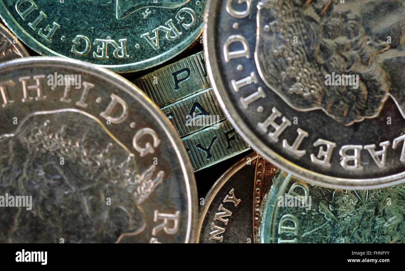 ONE POUND COIN EDGE LETTERS SPELLING WORD 'PAY' WITH OTHER COINS RE THE NATIONAL LIVING WAGE MINIMUM PAYSLIPS SALARY TAX UK Stock Photo