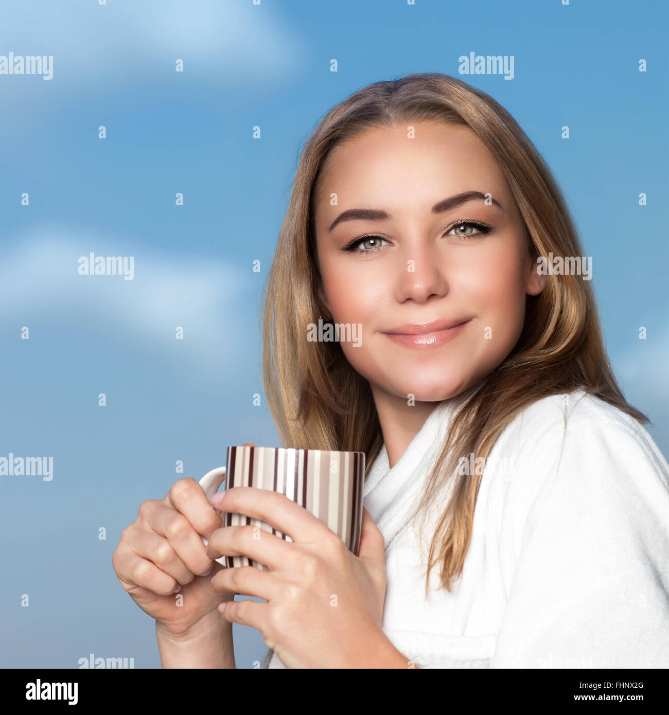 Portrait of pretty woman having morning coffee, wearing bathrobe and standing with mug in hands