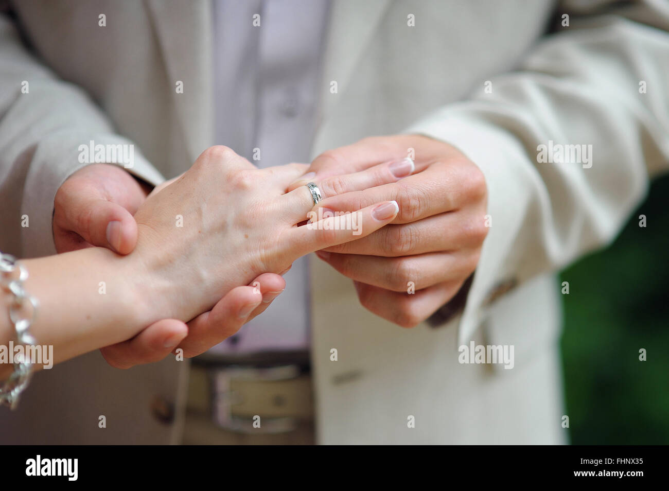 Hands with rings Groom putting golden ring on bride's finger Stock