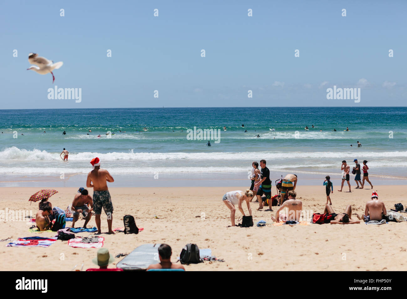 Christmas Eve on Manly Beach, Sunbathers with Santa Hats. Stock Photo