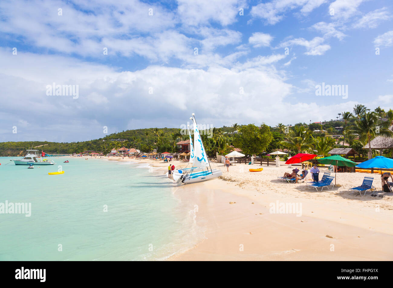 Panoramic view of Dickenson Bay, north Antigua, with parasols, sun loungers and Sandals sailing boats on the beach Stock Photo