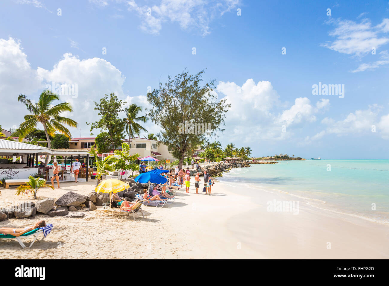 Dickenson Bay in north Antigua with sun parasols, white sand, blue sky and turquoise sea on a sunny day, Antigua and Barbuda Stock Photo