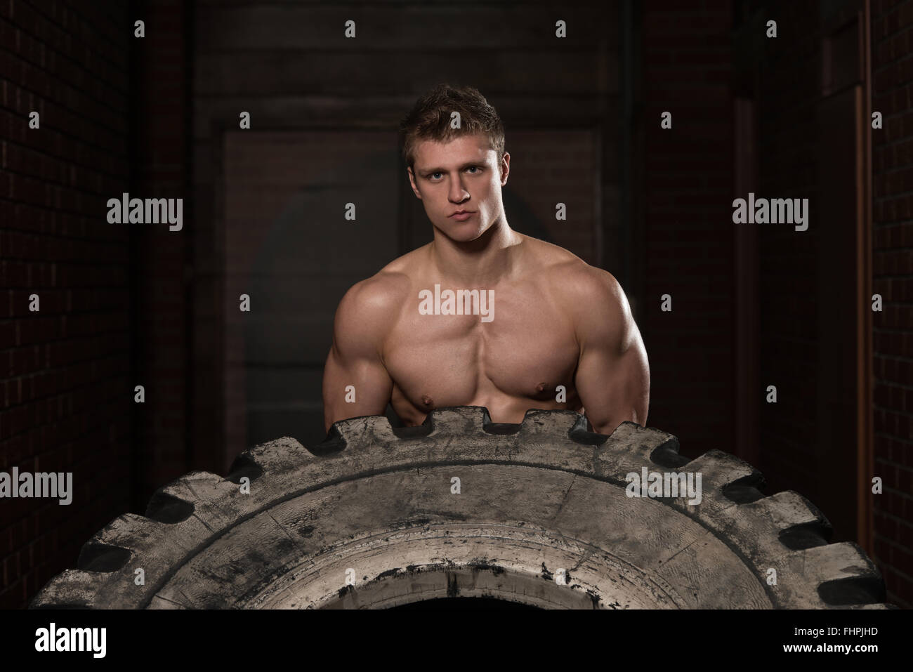 Young Muscular Man With Truck Tire Doing Crossfit Style Workout Turning