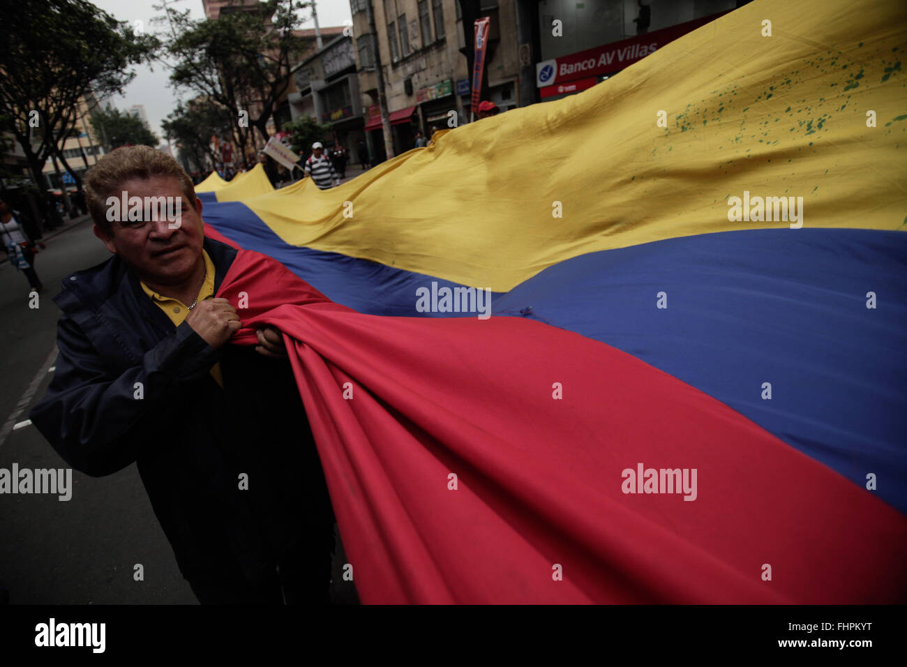 Bogota, Colombia. 25th Feb, 2016. A resident holds a national Colombian flag during a march called by student organizations and labor unions in Bogota, capital of Colombia, on Feb. 25, 2016. Hundreds of citizens, students and leaders of labor unions demonstrated against the value-added tax increase, the low increase to minimum wage, the mishandling of higher education and the sale of national companies. © Jhon Paz/Xinhua/Alamy Live News Stock Photo