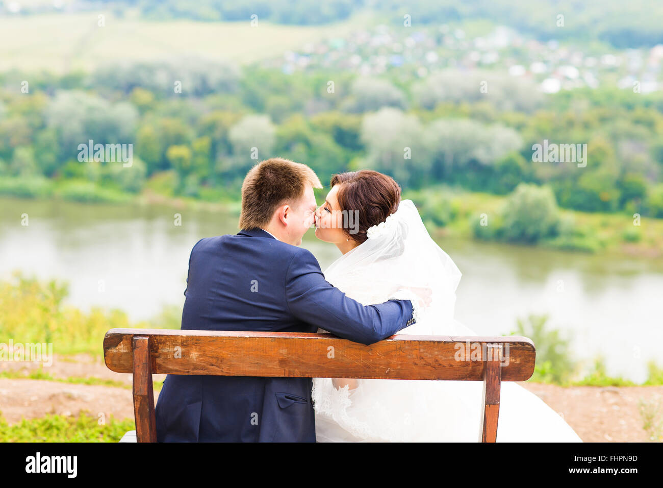 Romantic wedding couple sitting on a bench in the park Stock Photo - Alamy