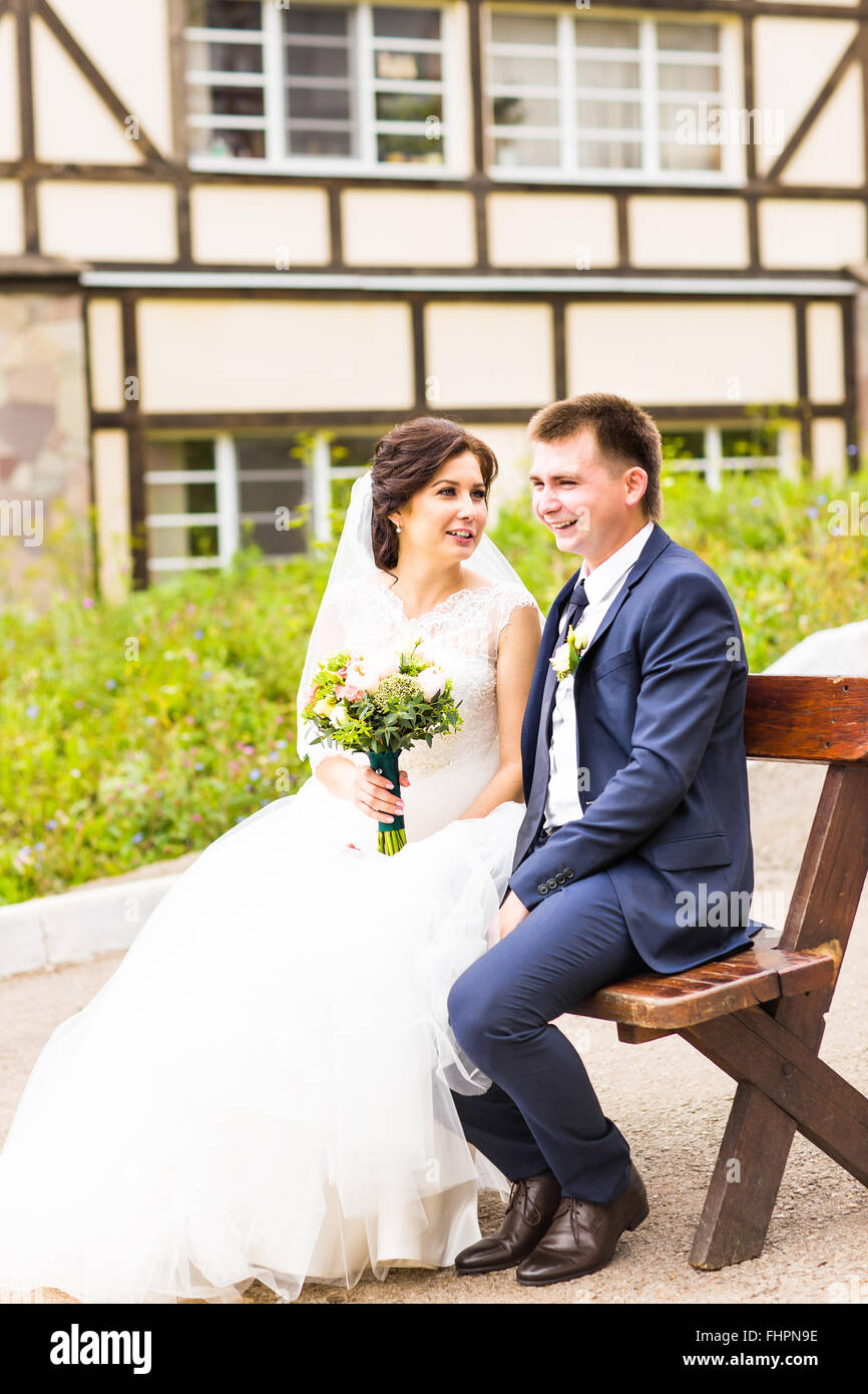Romantic wedding couple sitting on a bench in the park Stock Photo - Alamy