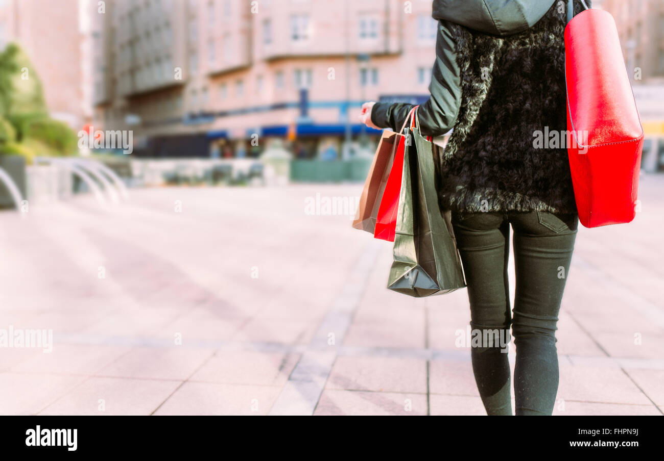 Back view of young woman carrying shopping bags Stock Photo