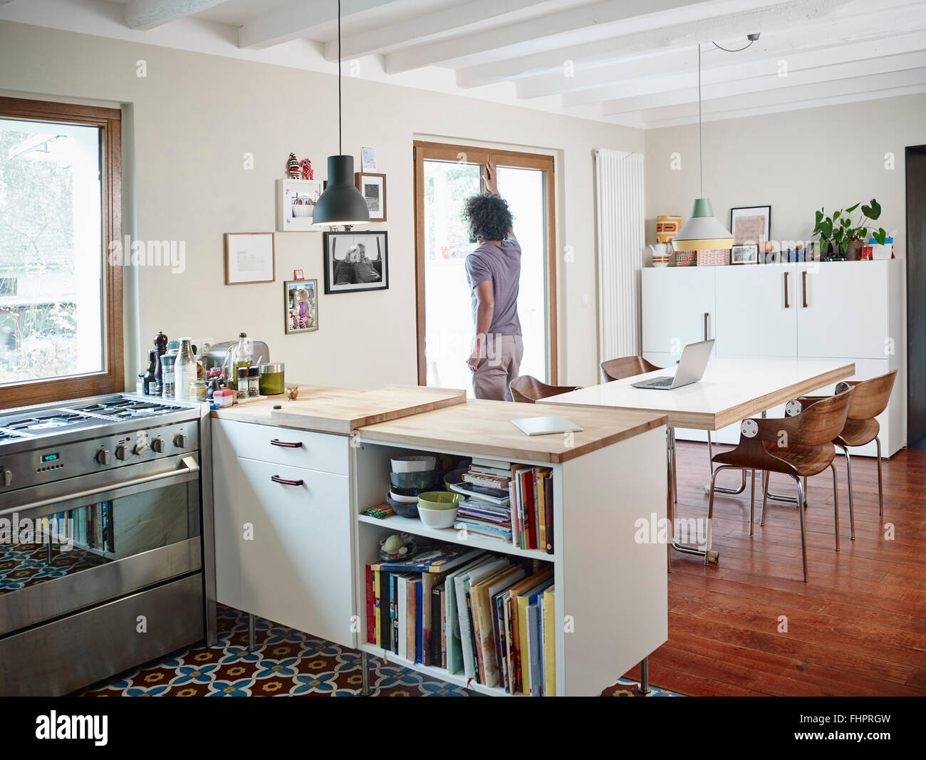 Young man looking out of window in open plan kitchen Stock Photo