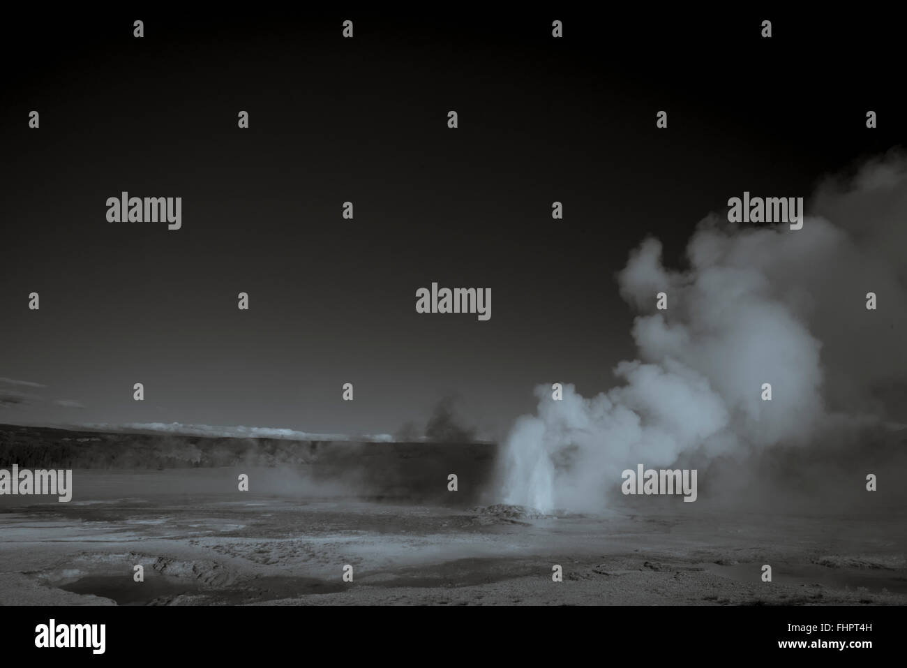 Black and white shot of a geyser erupting. Billowing cloud of steam and ...