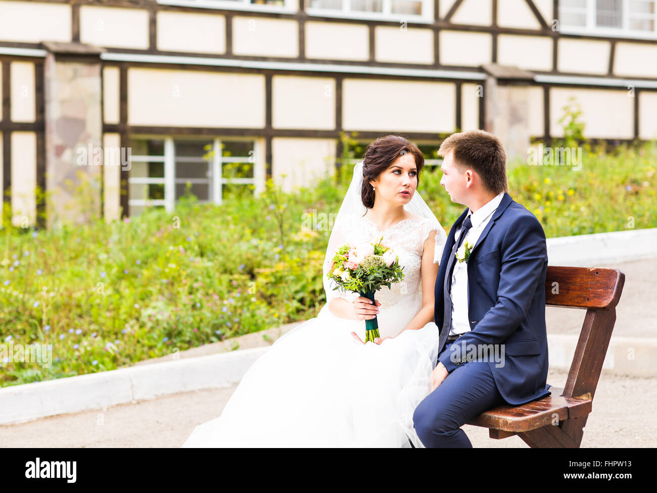 Romantic wedding couple sitting on a bench in the park Stock Photo - Alamy