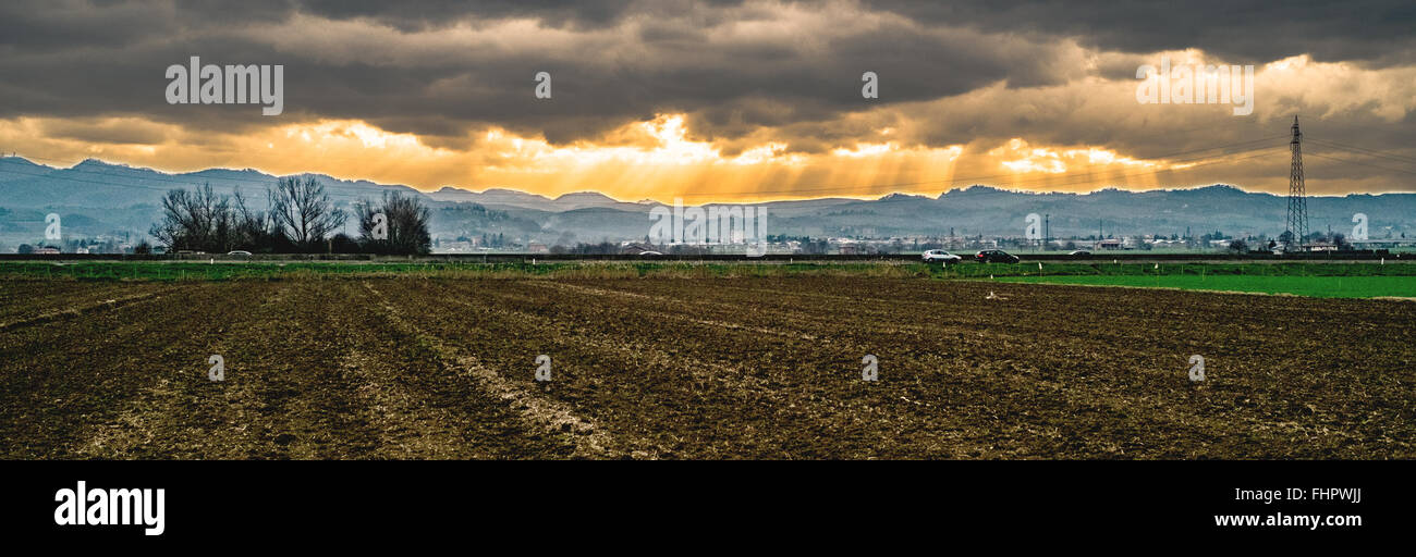 Cloudy weather on the plain with hills on background Stock Photo