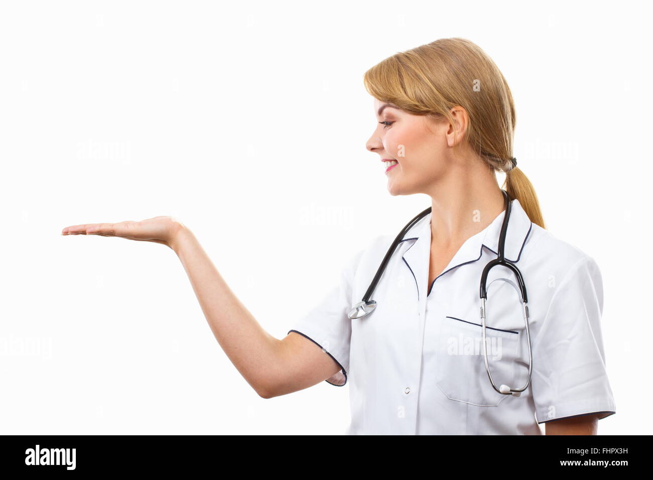 Smiling woman doctor in white apron with stethoscope holding empty hand