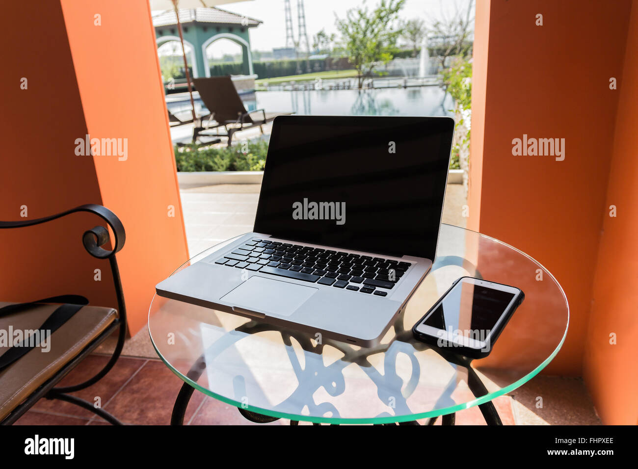 Laptop computer, phone ,books and plant on the table in swimming pool