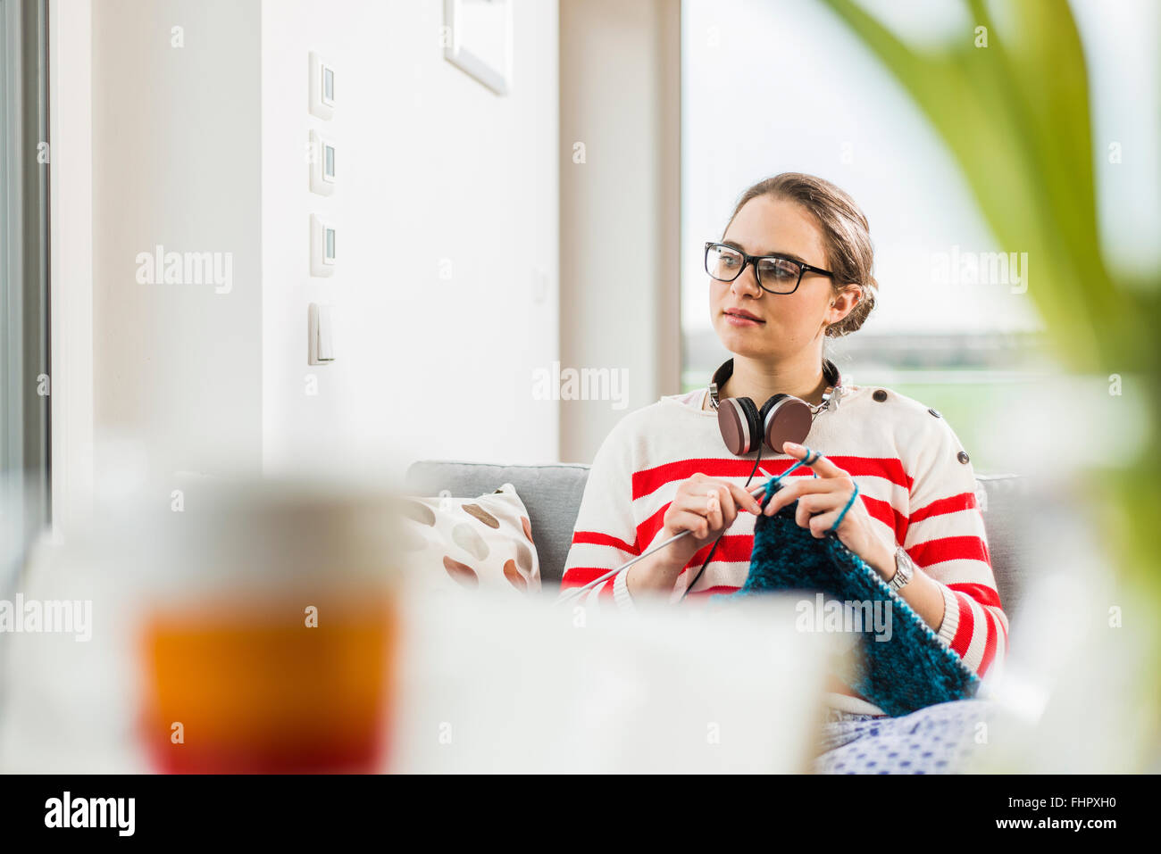 Young woman sitting on couch knitting Stock Photo - Alamy