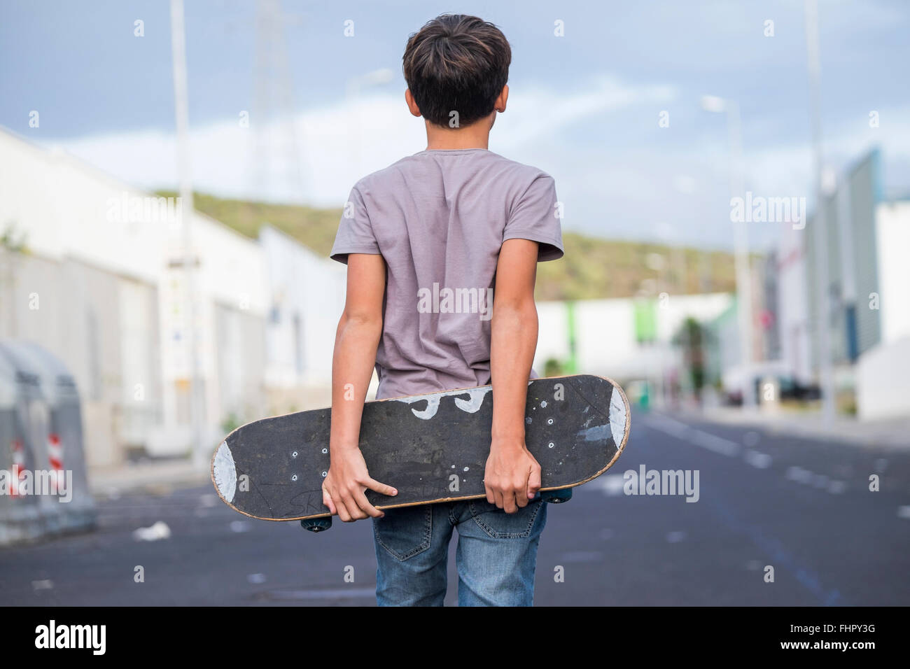 Spain, Tenerife, back view of boy holding his skateboard behind his back  Stock Photo - Alamy