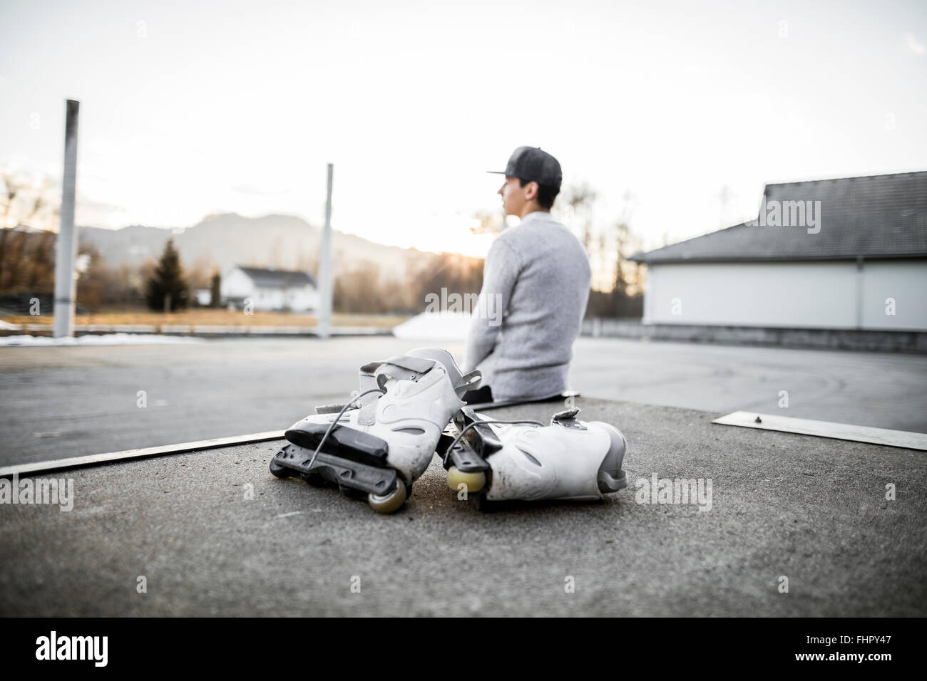 Young man sitting on ramp with inline skates Stock Photo