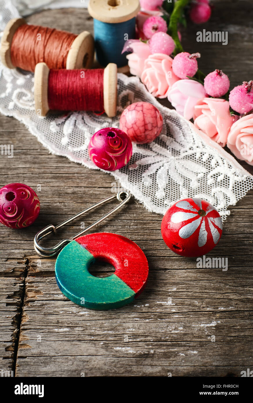 Beads and spool of thread, piece of lace on textured wooden background Stock Photo