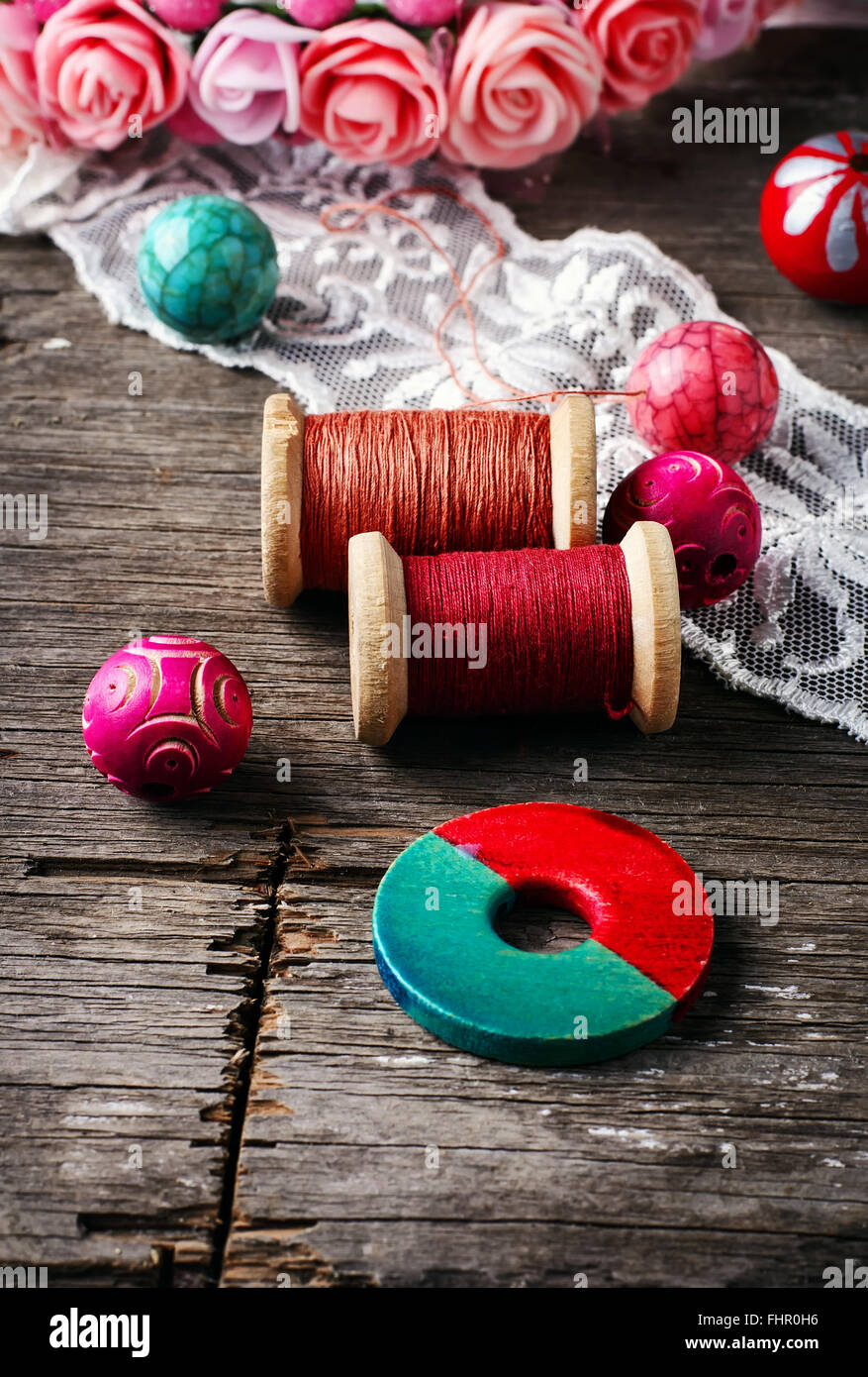 Beads and spool of thread, piece of lace on textured wooden background Stock Photo