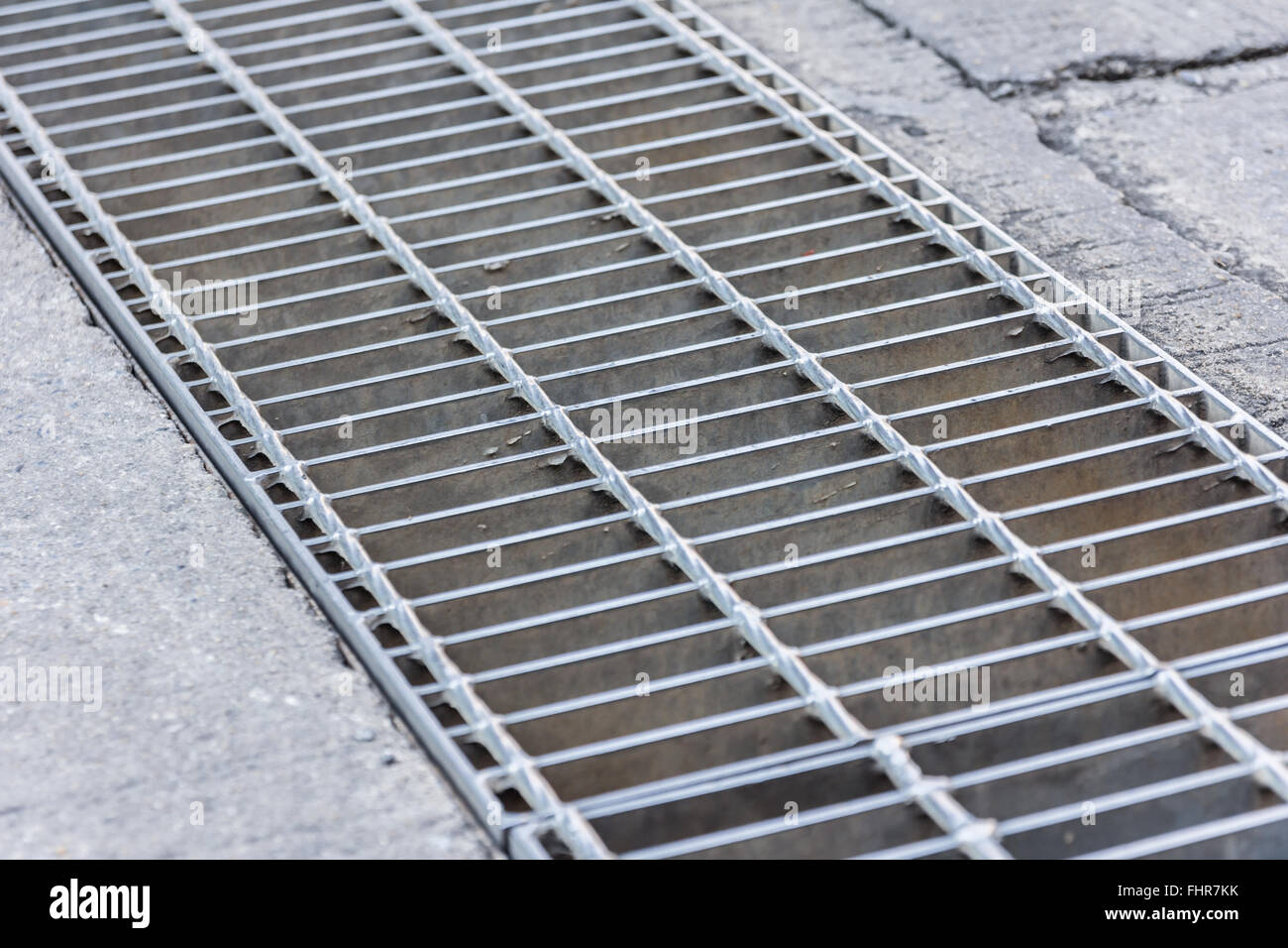 Black and white close up of a sidewalk subway grate with shallow depth of field. Stock Photo