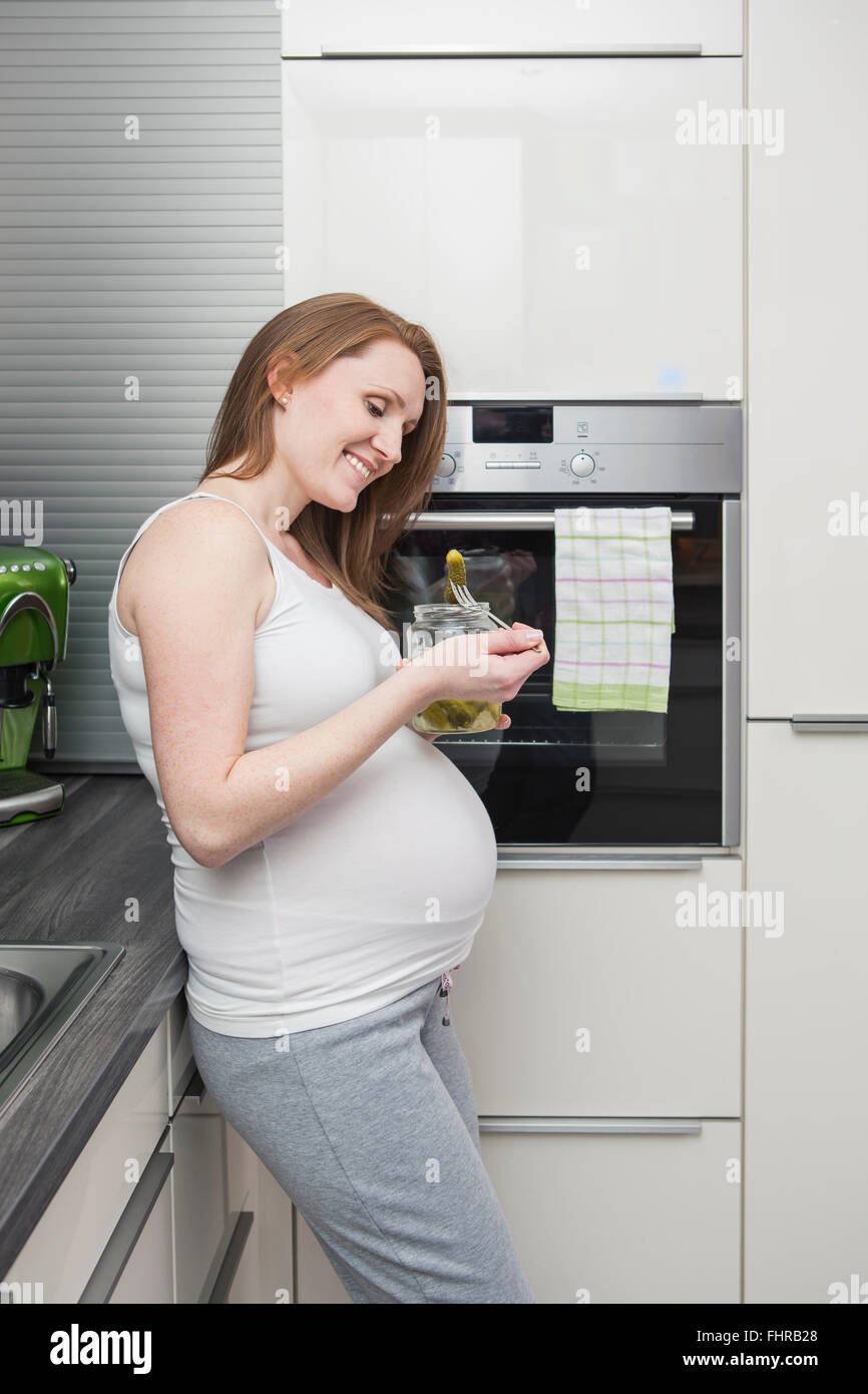 Pregnant woman in kitchen eating gherkins Stock Photo Alamy