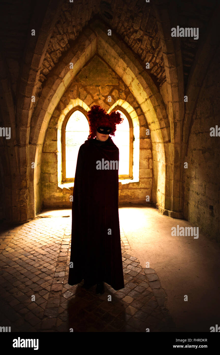 female figure wearing red wig standing in castle Stock Photo