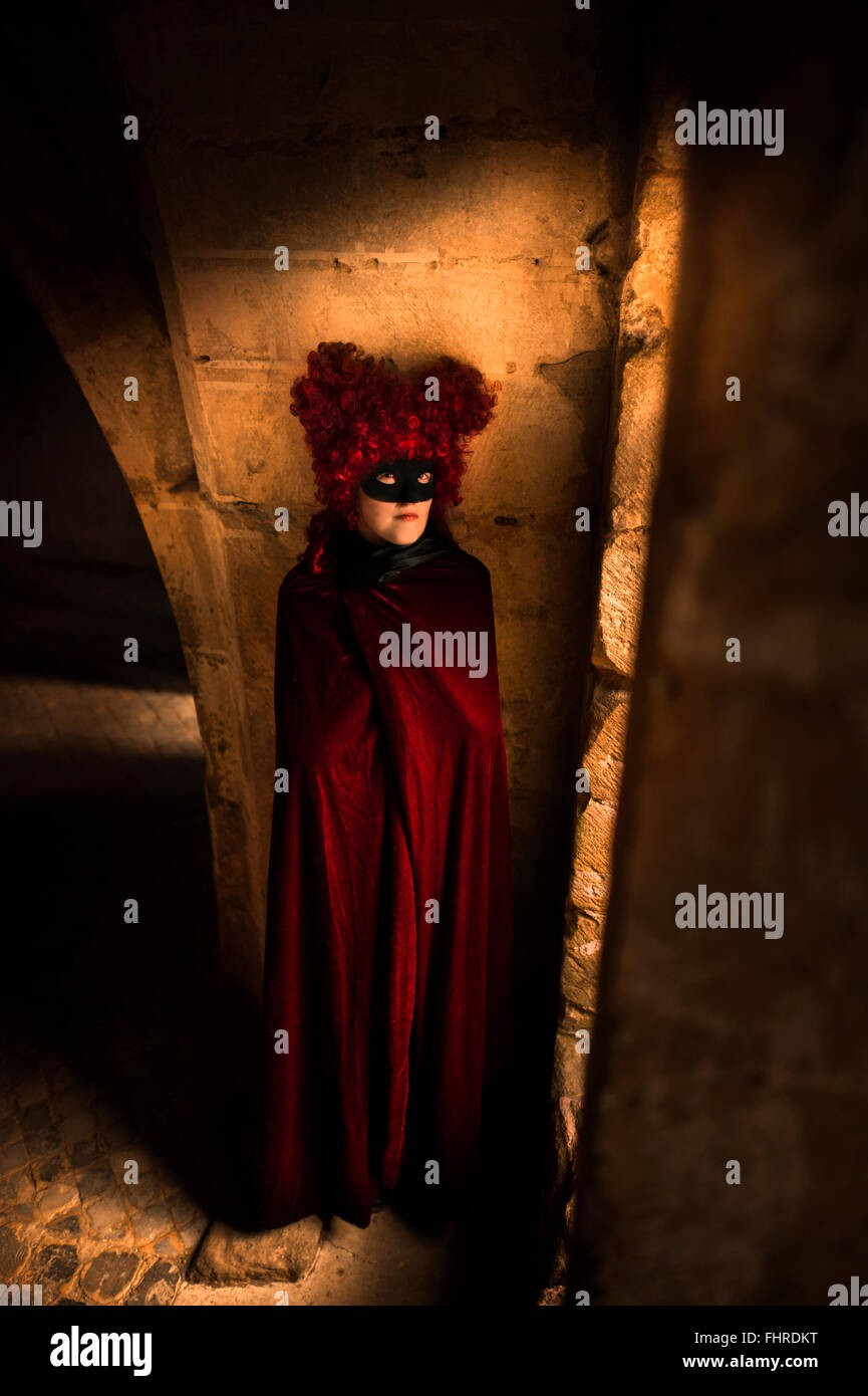 female figure wearing red wig standing in castle by the window Stock Photo