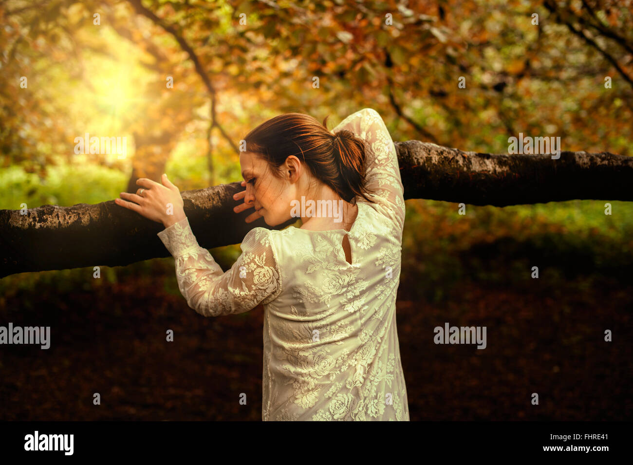 young woman in park leaning on tree branch Stock Photo