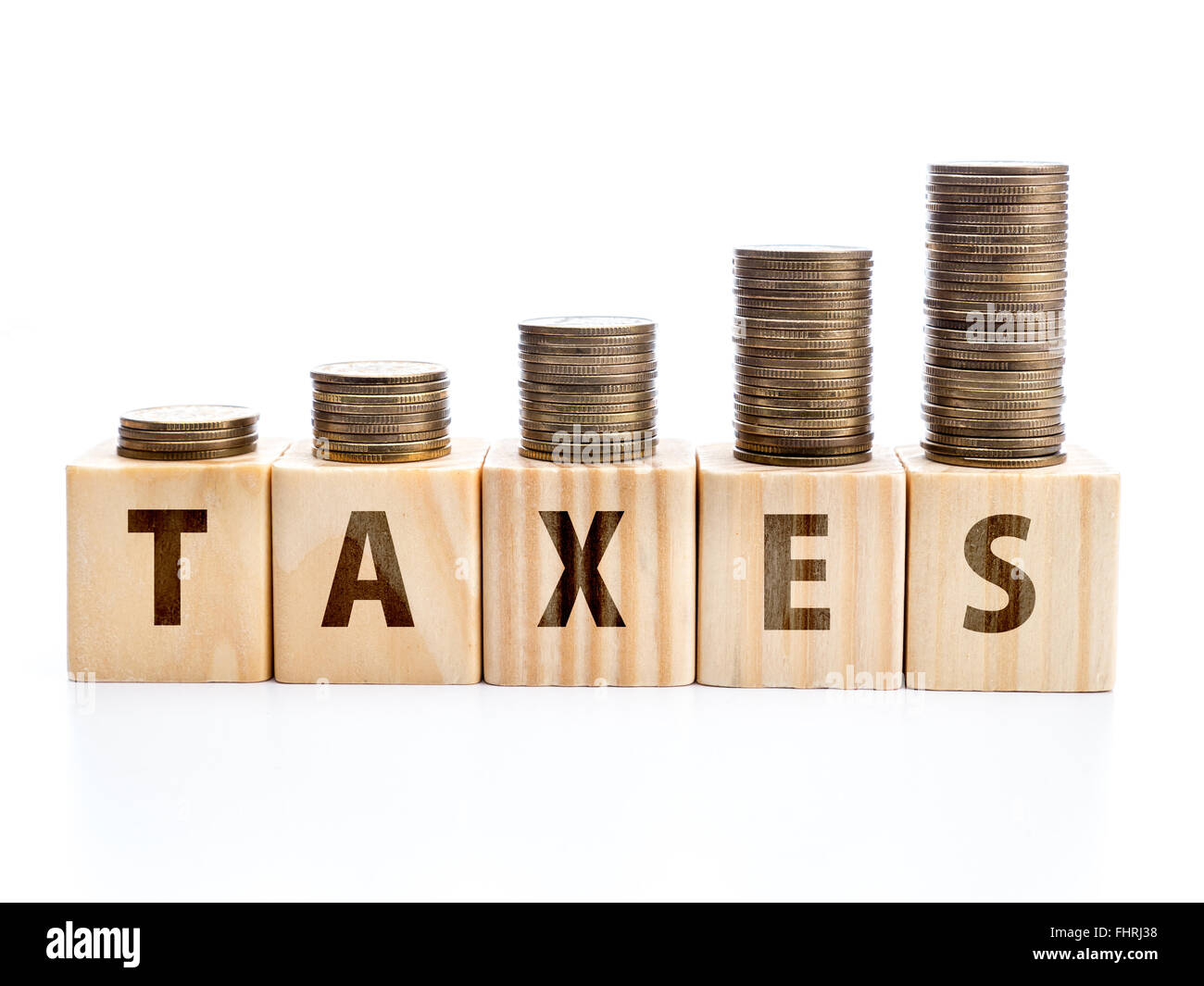 Piles of coins arranged in increased manner placed on wooden block with TAXES word Stock Photo
