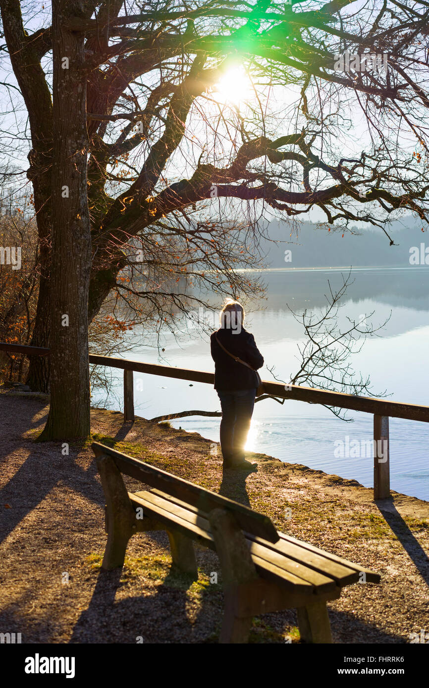 Germany, Bavaria, Lake Staffelsee, senior woman at lakeshore in backlight Stock Photo