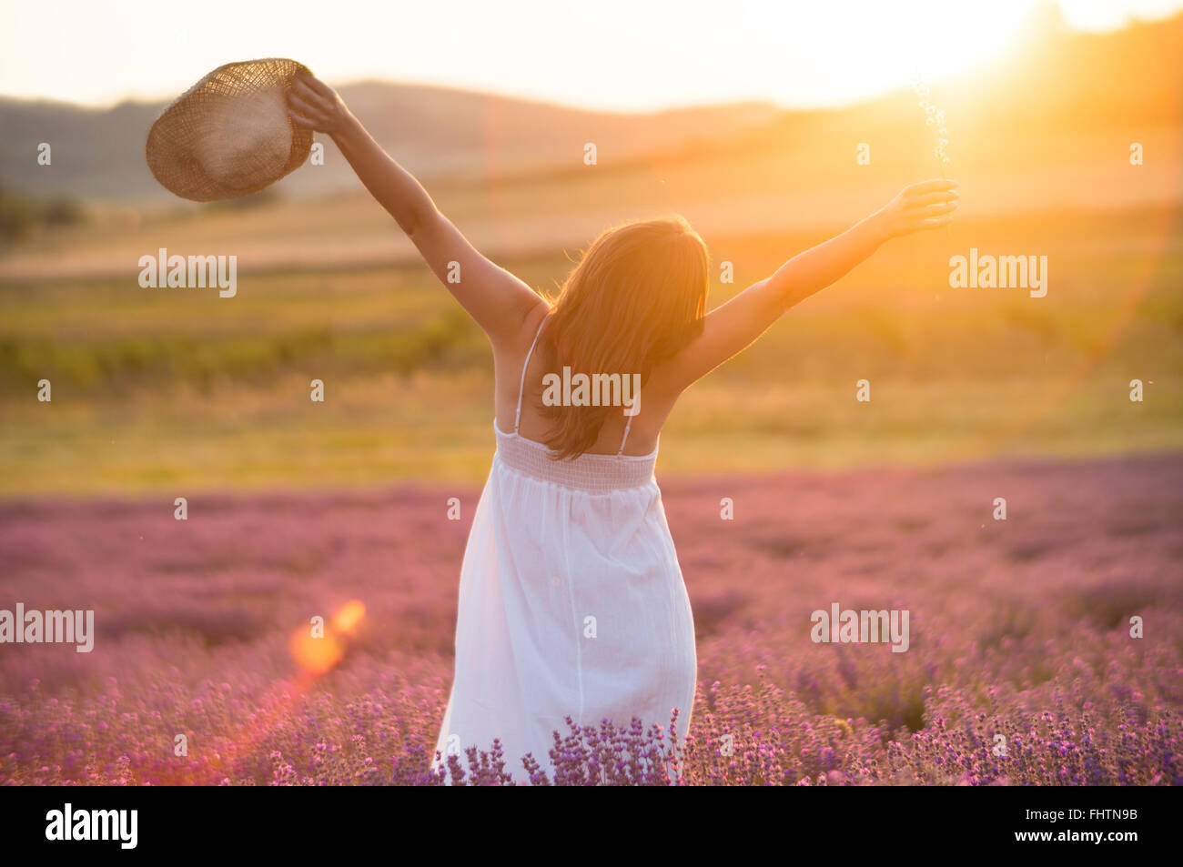 Beautiful young woman with a white dress and a straw hat standing in ...