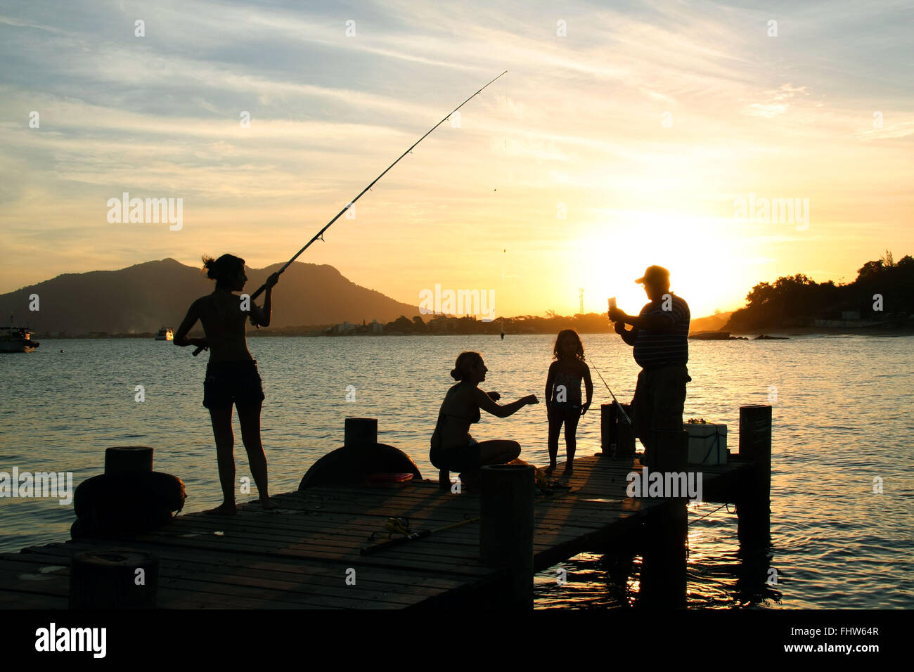 Family fishing on the pier at Boca da Barra Beach of the Oyster River - RJ Stock Photo
